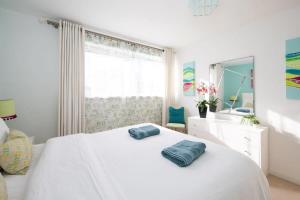 a bedroom with a white bed with two pillows on it at Sunny & Modern Near the Beach & Village w Parking in East Wittering