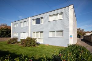 a gray building with white windows in a yard at Sunny & Modern Near the Beach & Village w Parking in East Wittering