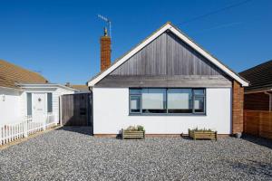 a white house with a black roof at Designer Family Escape Hot Tub Steps to Beach in East Wittering