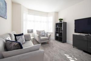 a living room with a couch and a flat screen tv at Charming & Modern City Escape Garden Parking in Chichester