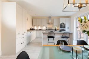 a kitchen with white cabinets and a table and chairs at Charming & Modern City Escape Garden Parking in Chichester