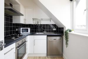 a white kitchen with a sink and a microwave at Lovely Selsey apartment with sea views sleeps 4 in Selsey