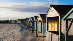 a row of beach huts on a sandy beach at Lovely Selsey apartment with sea views sleeps 4 in Selsey