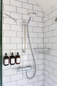 una ducha con cabezal de ducha en una pared de azulejos blancos en Camber - King Room in Gastro Pub, en West Wittering