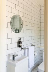 een wit betegelde badkamer met een wastafel en een spiegel bij Camber - King Room in Gastro Pub in West Wittering
