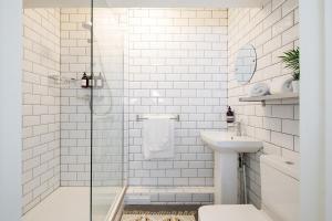 a white tiled bathroom with a sink and a shower at Stocker - King Room in Gastro Pub in West Wittering
