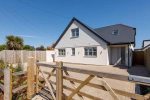 a white house with a wooden fence in front of it at Delightful Seaside Hideaway 5 Mins to Beach in Earnley