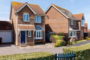 uma casa de tijolos com uma porta azul em Wonderful Seafront Home - Panoramic Ocean Views em Selsey