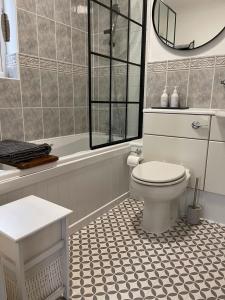 a bathroom with a toilet and a tub and a mirror at Wonderful Seafront Home - Panoramic Ocean Views in Selsey
