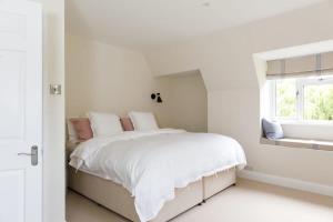 a white bedroom with a bed and a window at Stunning 5BR Home with Pool - 5 min to Beach in West Wittering