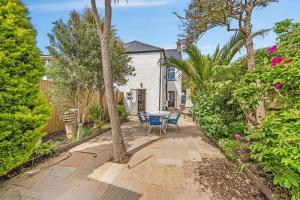 a patio with a table and chairs in a garden at Lovely Seaside Villa & Gardens 40 Metres to Beach in Felpham