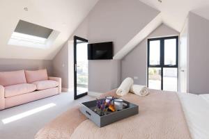 a bedroom with a pink bed and a pink couch at Luxury designer coastal home for 10 with hot tub in West Wittering