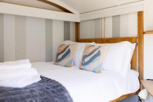 1 dormitorio con 1 cama con sábanas y almohadas blancas en Gorgeous Shepherds Hut - Walk to Beach & Pub, en West Wittering