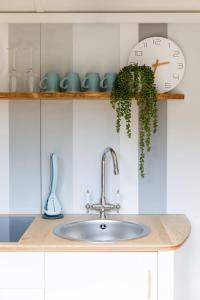 a kitchen counter with a sink and a clock and a plant at Gorgeous Shepherds Hut - Walk to Beach & Pub in West Wittering