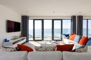 a living room with a couch and a tv and the ocean at The Sea House - Ultimate Seafront Living & Sunsets in Selsey