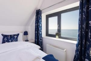 a bedroom with a bed and a window with the ocean at The Sea House - Ultimate Seafront Living & Sunsets in Selsey