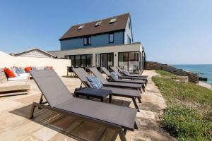 a row of lounge chairs in front of a house at The Sea House - Ultimate Seafront Living & Sunsets in Selsey