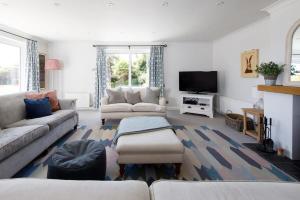 a living room with a couch and a tv at Ultimate beach house with pool in West Wittering in West Wittering