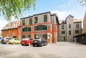 a building with cars parked in a parking lot at Stylish City Centre Apartment with Sauna in Chichester