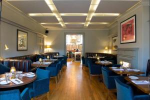 a restaurant with wooden tables and blue chairs at Stylish City Centre Apartment with Sauna in Chichester