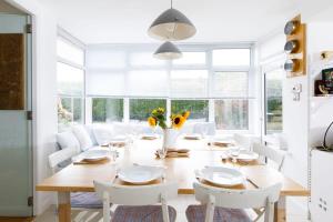 a dining room with a wooden table and white chairs at Secluded rural retreat close to beach - sleeps 12 in Earnley