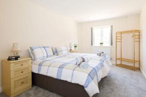 a bedroom with a bed with blue and white sheets at Countryside Bungalow for 4 Close to Beaches in Birdham