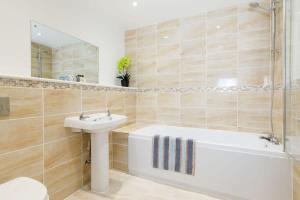 a bathroom with a white tub and a sink and a mirror at Countryside Bungalow for 4 Close to Beaches in Birdham