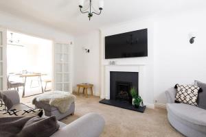 Modern & Stylish Seaside Escape في Earnley: غرفة معيشة مع موقد وتلفزيون على الحائط