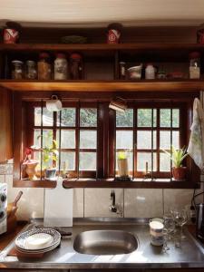eine Küche mit einem Waschbecken und zwei Fenstern darin in der Unterkunft Sítio em área rural, ao pé da Serra Gaúcha. in Três Coroas