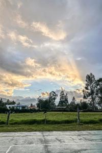 a rainbow in the sky over a field with trees at ART HOUSE Hacienda San Antonio in Cajamarca