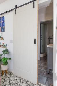 a sliding barn door in a bathroom with a plant at Beachside Retreat for 8 Close to Village in East Wittering