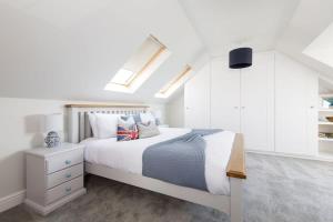 a white bedroom with a bed and a white cabinet at Beach house for 10 with hot tub & garden in West Wittering