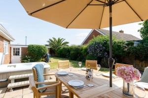 a wooden table with an umbrella on a patio at Beach house for 10 with hot tub & garden in West Wittering