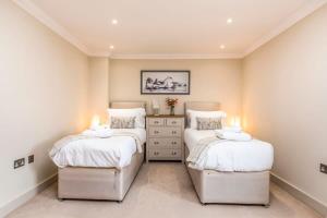 a bedroom with two twin beds with white sheets at Stylish 3 Bed with Double Carport in Fishbourne