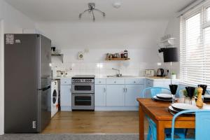 cocina con electrodomésticos blancos y mesa de madera en Two-bed beachside apartment West Wittering, en West Wittering