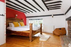 a bedroom with a wooden bed and a red wall at Tranquil Luxe in Country Cottage in Bosham