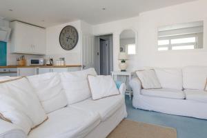 a white couch in a living room with a clock on the wall at Two Bed Seafront Escape in East Wittering in East Wittering