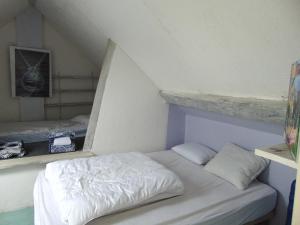 ein weißes Bett in einem Zimmer mit Dachgeschoss in der Unterkunft Simple cottage bucolique au calme 