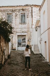 une femme debout dans une ruelle devant un bâtiment dans l'établissement Manili Boutique Suites & Villas, à Archanes