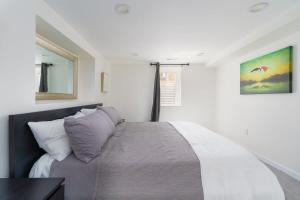 1 dormitorio con cama y espejo en la pared en Sleek & Stylish Apt Steps From Bluebird Theater en Denver