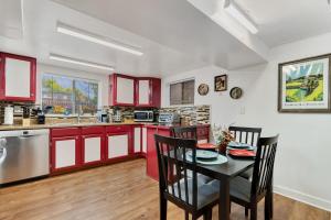 cocina con armarios rojos, mesa y sillas en Cozy & Spacious Apartment Steps From Regis, en Denver