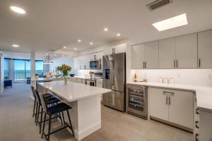a kitchen with white cabinets and a large island with bar stools at Bella Luna, 2 bed and 2 bath beachfront condo in Bradenton Beach