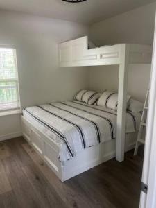 een witte slaapkamer met een stapelbed en een raam bij Waterfront house on Sam Rayburn - Sleeps 23! in Brookeland