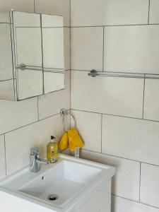 ein weißes Badezimmer mit einem Waschbecken und einem Spiegel in der Unterkunft City Dreams in Croydon