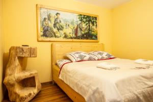 a bedroom with a bed with a painting on the wall at Poronin Mountain Apartments in Poronin