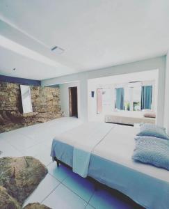 1 dormitorio con 1 cama grande y pared de piedra en POUSADA MIRANTE DO VALE en Serra de São Bento