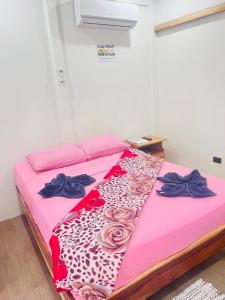 a bed in a room with pink sheets and roses at Apartamentos en el Centro de Puerto Viejo in Puerto Limón