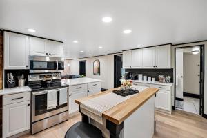 a large kitchen with white cabinets and a wooden table at Charming & Updated Garden Level in Heart of Denver in Denver