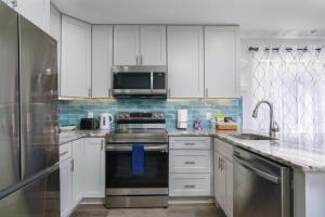 a kitchen with white cabinets and a stove and a microwave at Remodeled Corner Unit 2 2 Overlooking the Lagoon in Hilton Head Island