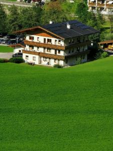 a building with solar panels on top of a green field at Apart Geisler in Mayrhofen